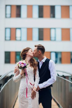 Gelin ve damat yürüyüş şehir, düğün günü, evlilik kavramı. Gelin ve damat kentsel arka planda. Genç çift bir merdivende düğün günü olacak.