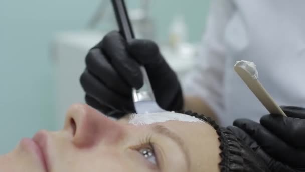 Gros plan du visage du visiteur du salon de beauté, masque noir est appliqué sur le visage avec un bâton en bois spécial — Video