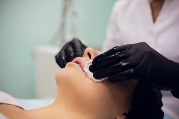 Wipe with sterile napkin face. Young woman receiving treatments in beauty salons. — Stock Photo, Image