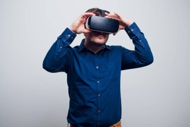 Genç adam dokunmaya çalışıyorum Vr gözlük kulaklık kullanarak sanal gerçeklik nesneleri. İzole beyaz arka plan.