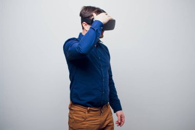 Genç adam dokunmaya çalışıyorum Vr gözlük kulaklık kullanarak sanal gerçeklik nesneleri. İzole beyaz arka plan.