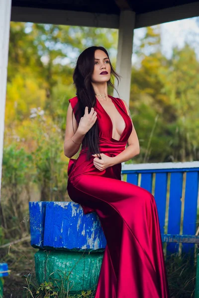 Uma mulher com um longo vestido vermelho sozinha na floresta. Imagem fabulosa e misteriosa de uma menina em uma floresta escura ao sol da noite. Pôr do sol, Princesa perdeu-se . — Fotografia de Stock