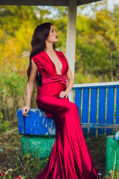 Woman in a long red dress alone in forest. Fabulous and mysterious image of a girl in a dark forest in the evening sun. Sunset, Princess got lost. — Stock Photo, Image