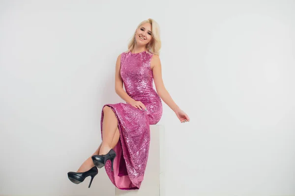 Mujer joven feliz en un vestido de noche celebrando sobre un fondo blanco . — Foto de Stock