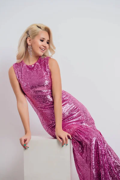 Mujer joven feliz en un vestido de noche celebrando sobre un fondo blanco . — Foto de Stock