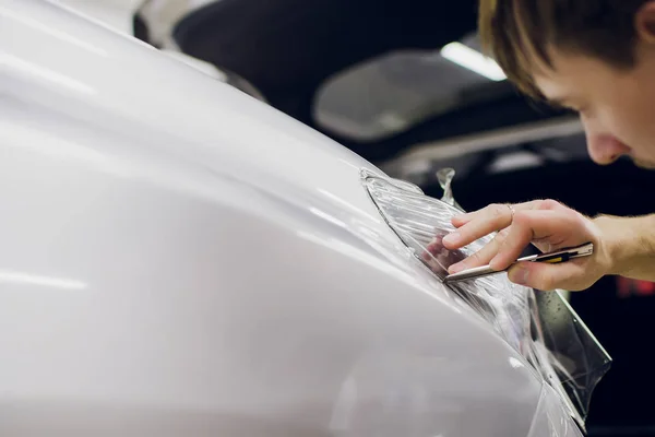 Worker hands installs car paint protection film.