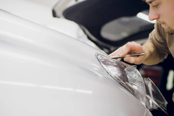 Worker hands installs car paint protection film.