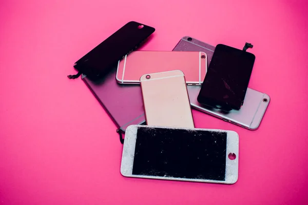 Telefone celular quebrado encontra-se em um fundo rosa . — Fotografia de Stock