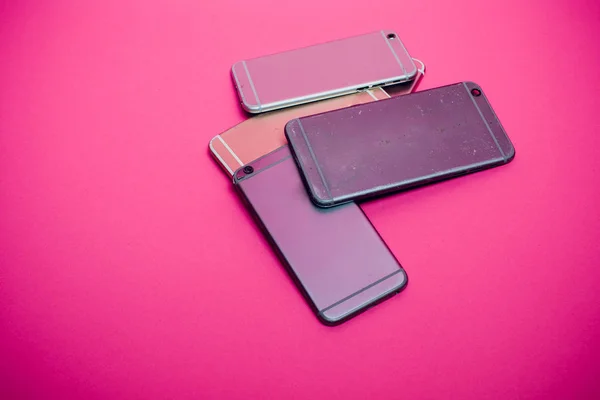 Telefone celular quebrado encontra-se em um fundo rosa . — Fotografia de Stock