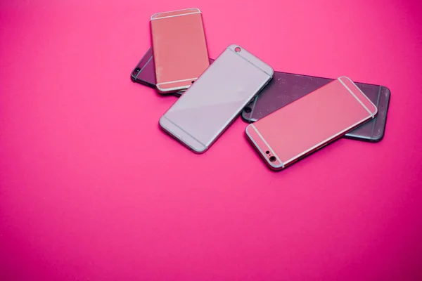 Telefone celular quebrado encontra-se em um fundo rosa . — Fotografia de Stock