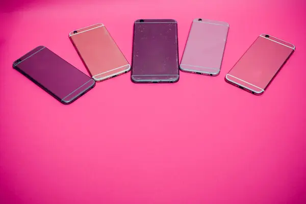 Telefone celular quebrado encontra-se em um fundo rosa . — Fotografia de Stock