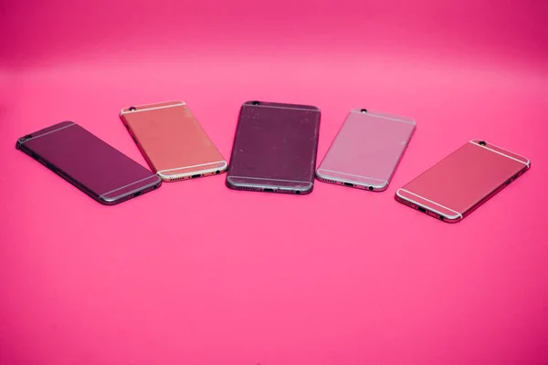 Сломанный мобильный телефон лежит на розовом фоне . — стоковое фото