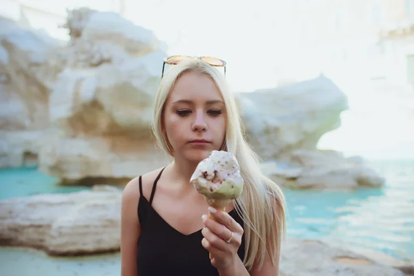 Ijs, jonge mooi blond meisje in een mooie outfit krijgt plezier van ijs. Smaakt een gele Eskimo. Plezier. Binnen. Witte achtergrond. — Stockfoto