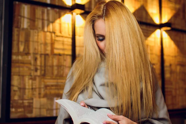 快乐的金发女孩坐着读一本书. — 图库照片