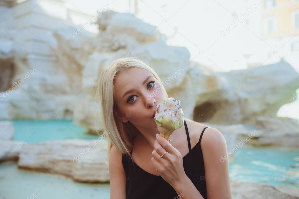 Ice cream, young beautiful blond girl in a bright outfit gets pleasure from ice cream. Tastes like a yellow Eskimo. Having fun. Indoor. White background.