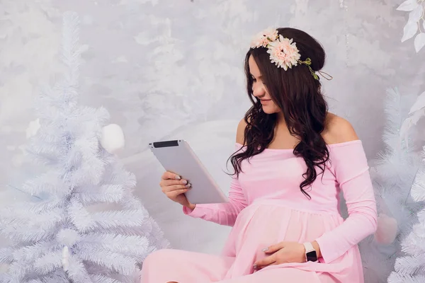 Piękna kobieta w ciąży jest przy użyciu cyfrowego tabletu. — Zdjęcie stockowe
