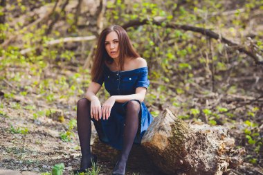 Doğa orman arka planda kamera önünde poz mavi elbiseli güzel genç kadın.