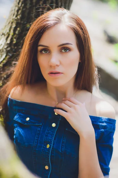 Hermosa mujer joven en vestido azul posando delante de la cámara en el fondo de la naturaleza en el bosque . — Foto de Stock
