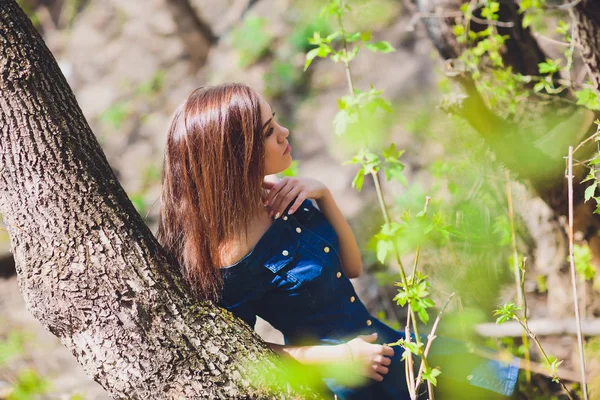 Красива молода жінка в блакитній сукні позує перед камерою на фоні природи в лісі . — стокове фото