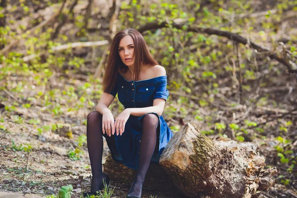 Schöne junge Frau in blauem Kleid posiert vor der Kamera auf Naturhintergrund im Wald. — Stockfoto