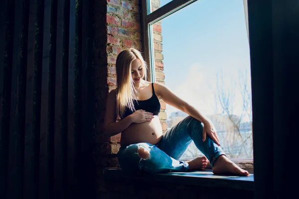 Νέοι όμορφη έγκυος γυναίκα κάθεται στο περβάζι στο σπίτι — Φωτογραφία Αρχείου