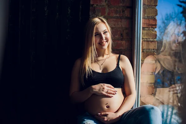 年轻美丽的孕妇，坐在家里的窗台上 — 图库照片