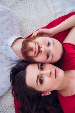 Güzel bir hamile kadın siyah iç çamaşırı üzerinde gri bir peçe yatıyor. Yatağın taze çiçeklerle bezenmiştir. Kız sarışın, o gülümsüyor vardır. Yukarıdan görüntülemek.