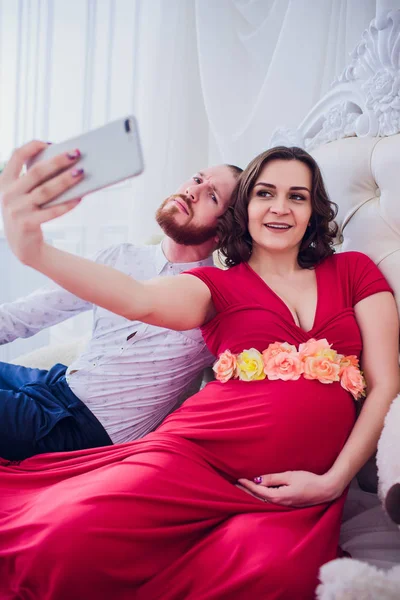 Чоловік і вагітна дружина змушують селфі сидіти на дивані. Вони обожнюють один одного. Вони вдома . — стокове фото