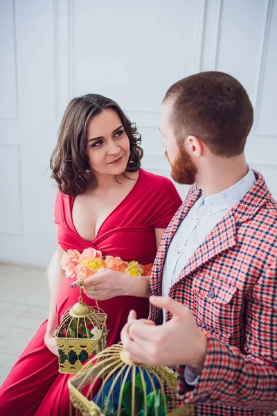 Beau jeune couple amoureux. Femme enceinte avec son mari assis à la maison. Ils sourient et regardent la caméra. L'homme tient les clés de l'appartement, et la fille nichoir . — Photo