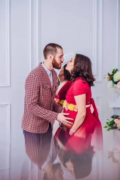 Foto eines glücklichen zukünftigen Vaters mit Blick auf seine schwangere Frau. Ehemann und Schwangere auf Spiegelhintergrund. — Stockfoto