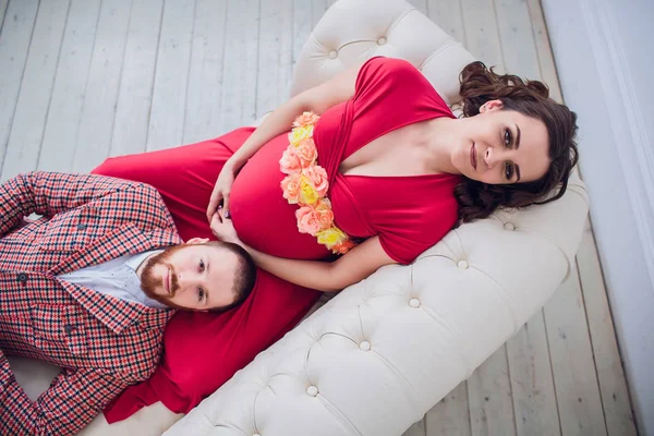 Jeune beau couple enceinte assis sur canapé vintage à la maison — Photo