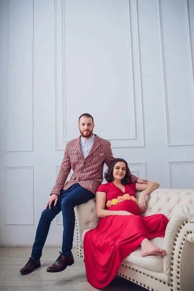 Молодая красивая беременная пара сидит дома на винтажном диване — стоковое фото