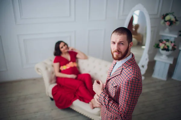 Portret van een mooie zwangere vrouw en haar man op de achtergrond. Zwangerschap concept — Stockfoto