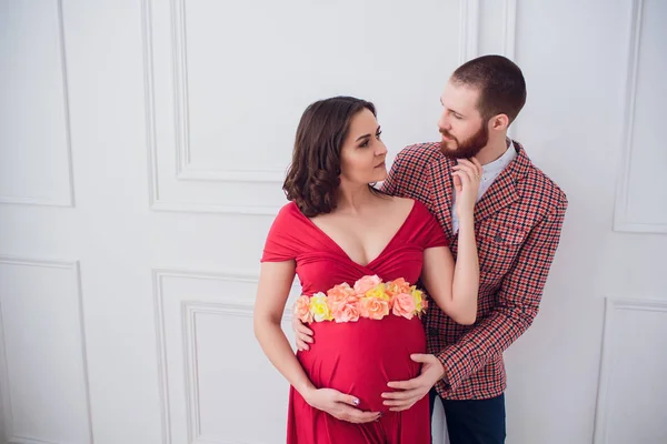 Elegante coppia incinta. incinta ragazza in abito rosso — Foto Stock