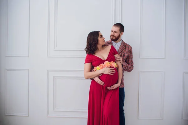 スタイリッシュな妊娠中のカップル。赤いドレスに妊娠中の女の子 — ストック写真