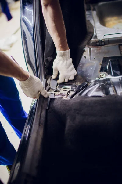 Ontmanteling van de vloer in de auto monteur verwijdert de verdiepingen in de auto — Stockfoto