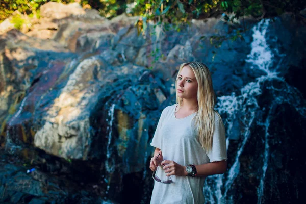 急いで滝の背景に対して石に黒い髪を持つ少女 — ストック写真