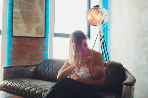 Amamantar Mujer lactante bebé en el interior del loft moderno. Diseño escandinavo minimalista. joven madre en ropa deportiva, entrenamiento en casa . —  Fotos de Stock