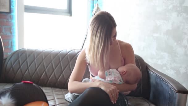 Breastfeeding Woman breast feeding baby in modern loft interior. Minimalistic scandinavian design. young mother in sportswear, workout at home. — Stock Video