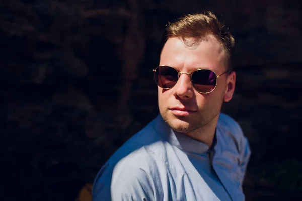 man in blue robe against background temple wall in sunglasses. CONCEPTION OF MODERN RELIGION