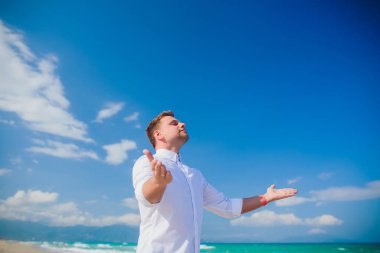 Yakışıklı adam beyaz kıyafetlerle deniz sahne poz