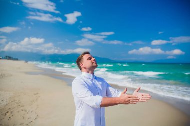 Yakışıklı adam beyaz kıyafetlerle deniz sahne poz