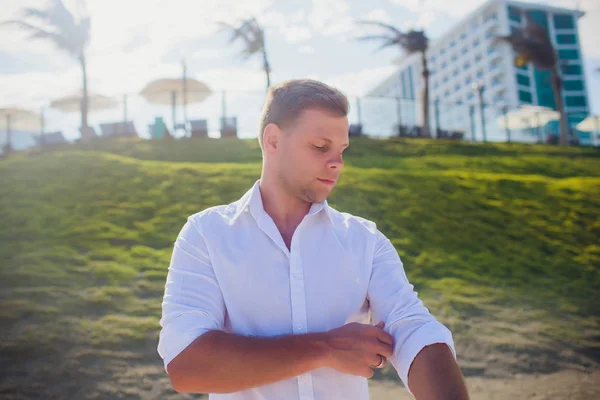 Красивий чоловік в білому одязі позує в морських пейзажах — стокове фото
