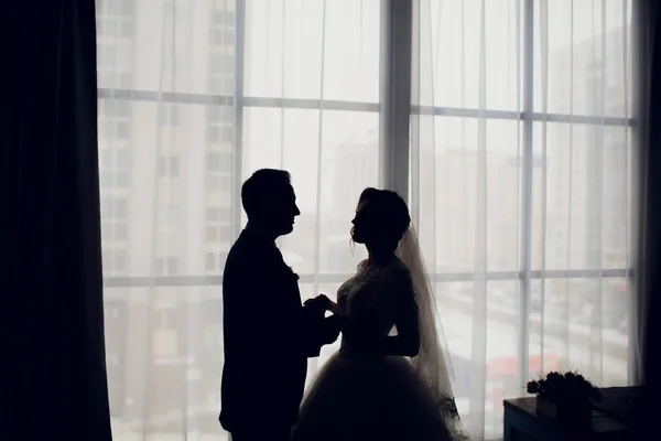 De kus van de bruid en bruidegom in het terug licht. Achtergrondverlichting. Stralende silhouet. Bruiloft sieraden. — Stockfoto