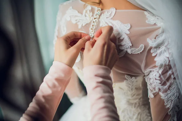 新婦付添人は花嫁の結婚式の服の背部の弓結びを作る — ストック写真