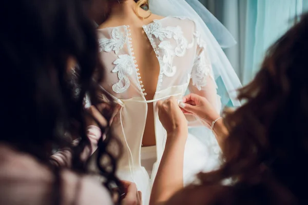 Bruidsmeisje maakt strik-knoop op de achterkant van bruiden trouwjurk — Stockfoto