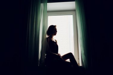 karanlık bir odada bir pencere yakınında bir düğün peçe kız