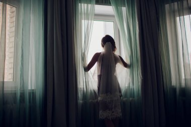 karanlık bir odada bir pencere yakınında bir düğün peçe kız