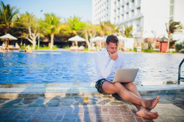 İşadamı takım elbise, bir elinde bir dizüstü bilgisayar ve bir bira, palet, açık mavi okyanus ile çevrili giyen okyanus şişme bir gemide başka bir kravat