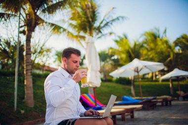 İşadamı takım elbise, bir elinde bir dizüstü bilgisayar ve bir bira, palet, açık mavi okyanus ile çevrili giyen okyanus şişme bir gemide başka bir kravat